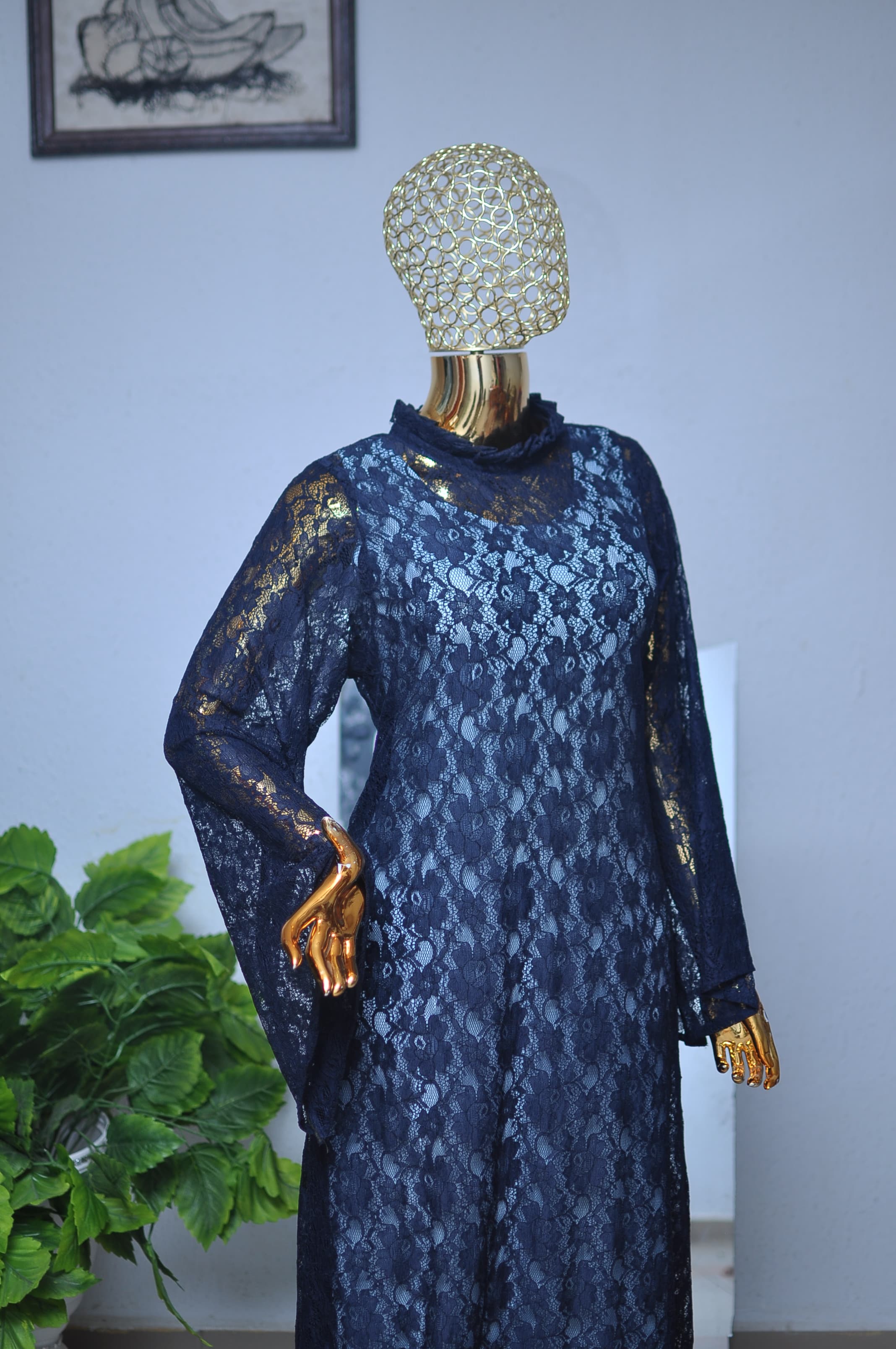 Navy floral lace gown with a ruffled, gold-flecked shoulder trim and a ruffled cuff.