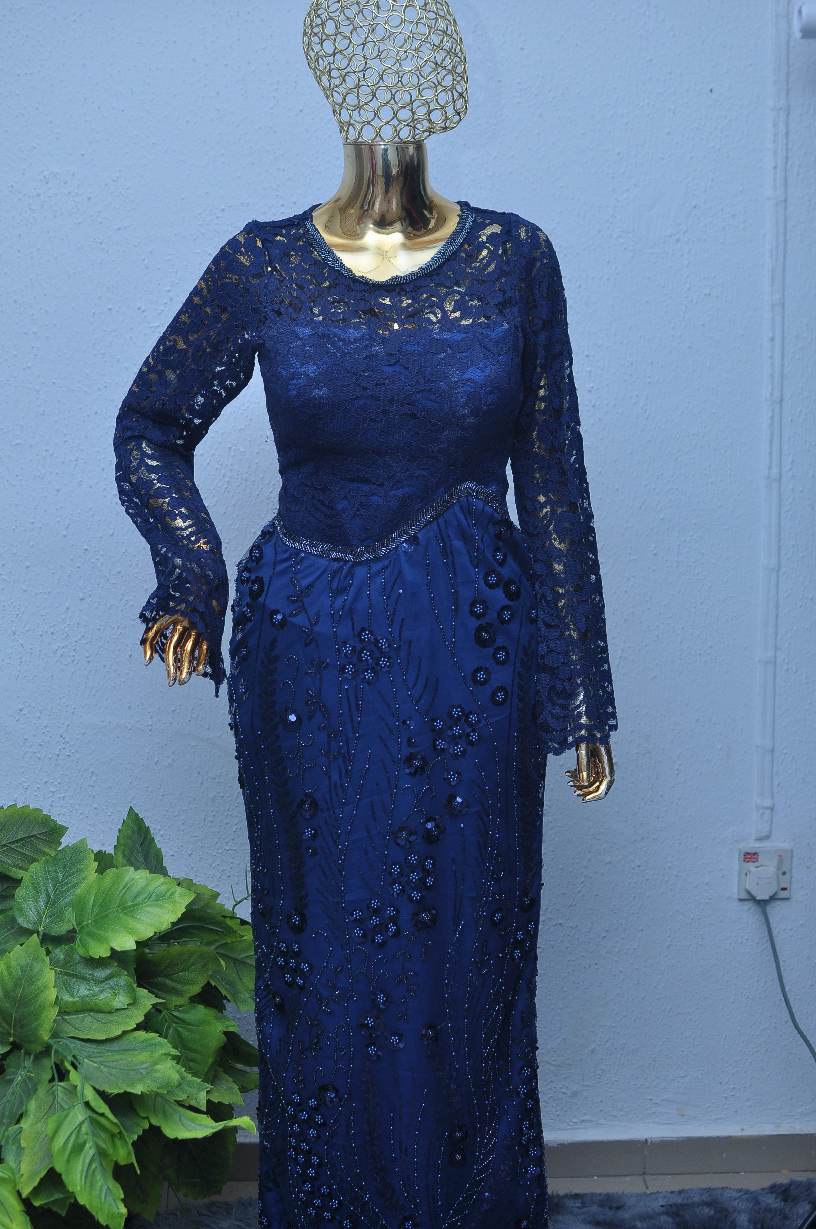 Navy lace gown with crystal beading in a trailing vine pattern and a cutout shoulder detail.