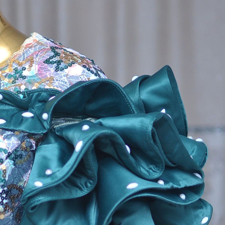 Close-up of tiered emerald satin ruffles edged with pearls.