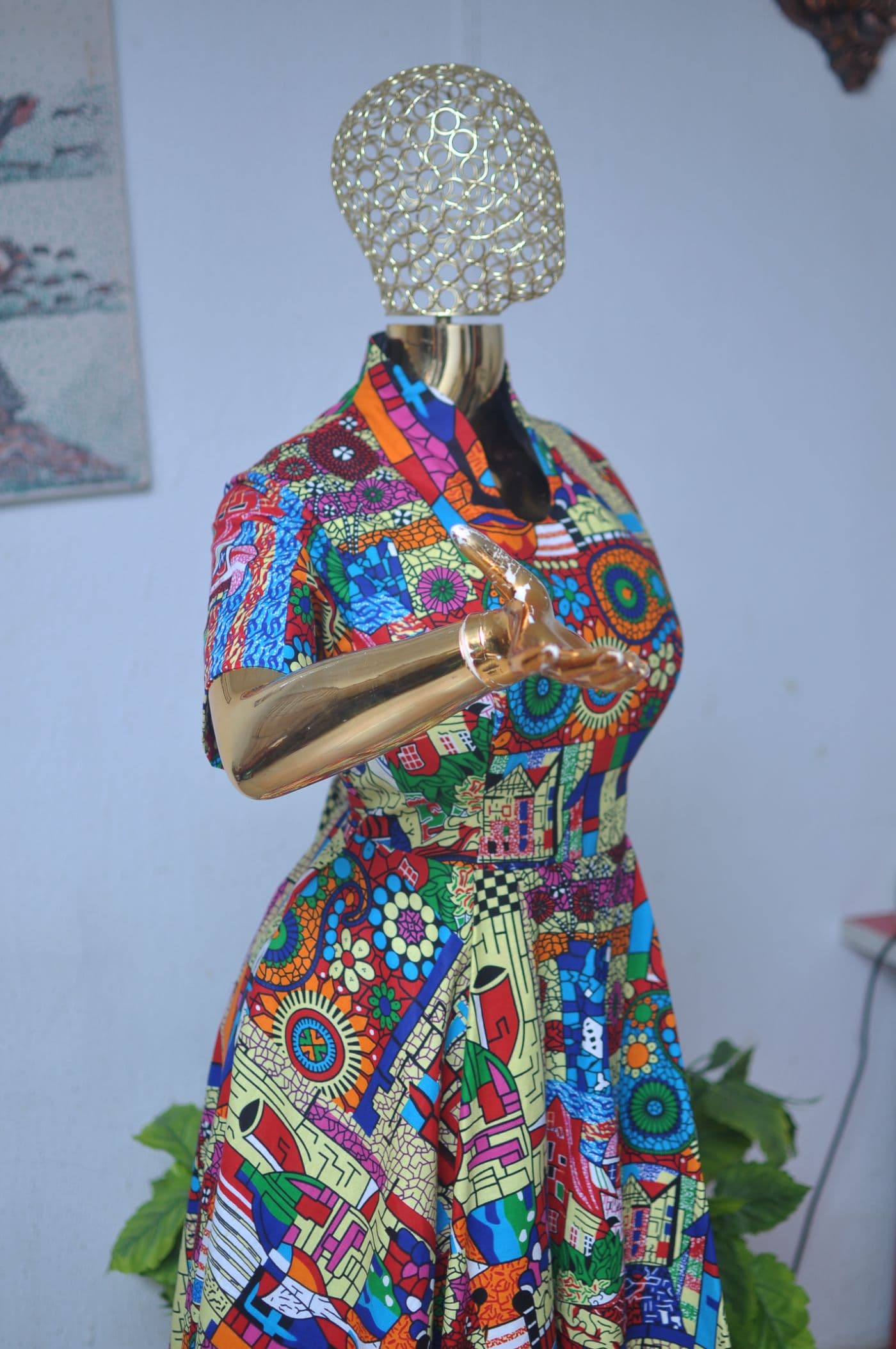 Abstract-print flared dress with short sleeves and belt, on a gold mannequin.
