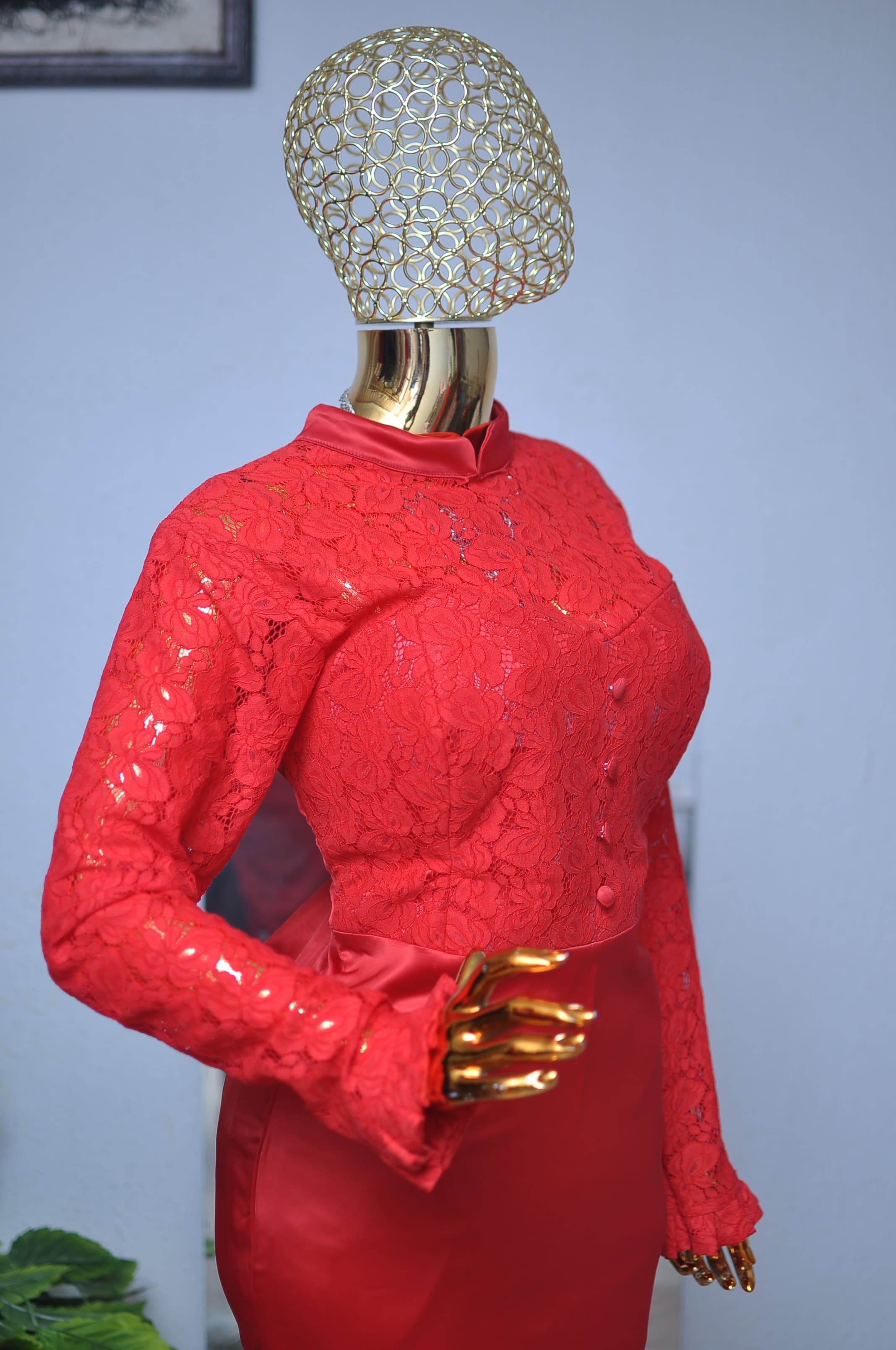 Red guipure lace jacket, buttoned to the throat, over a red satin skirt.