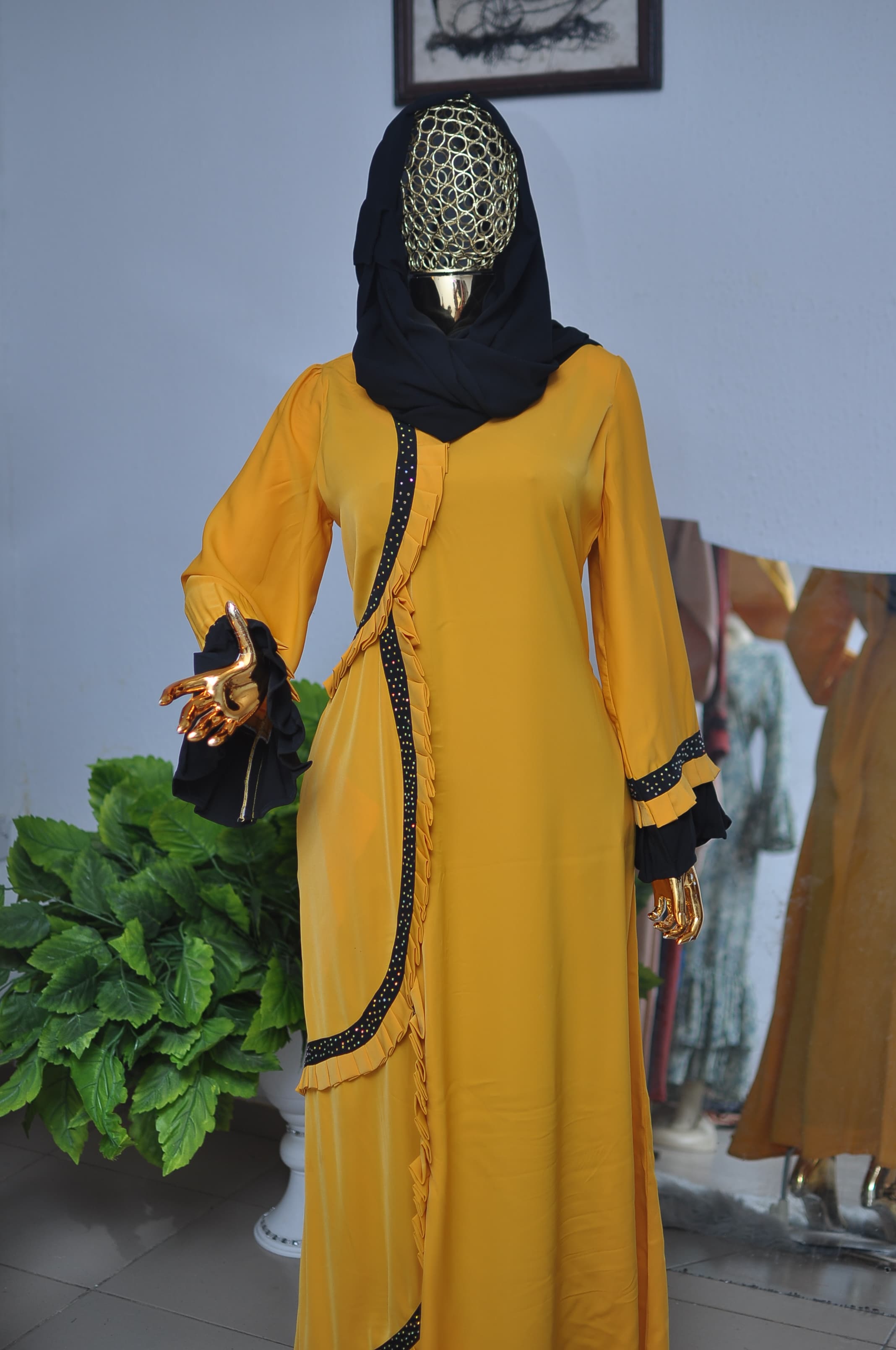 Mustard kaftan with a crystal-trimmed, pleated hem and a matching head wrap.