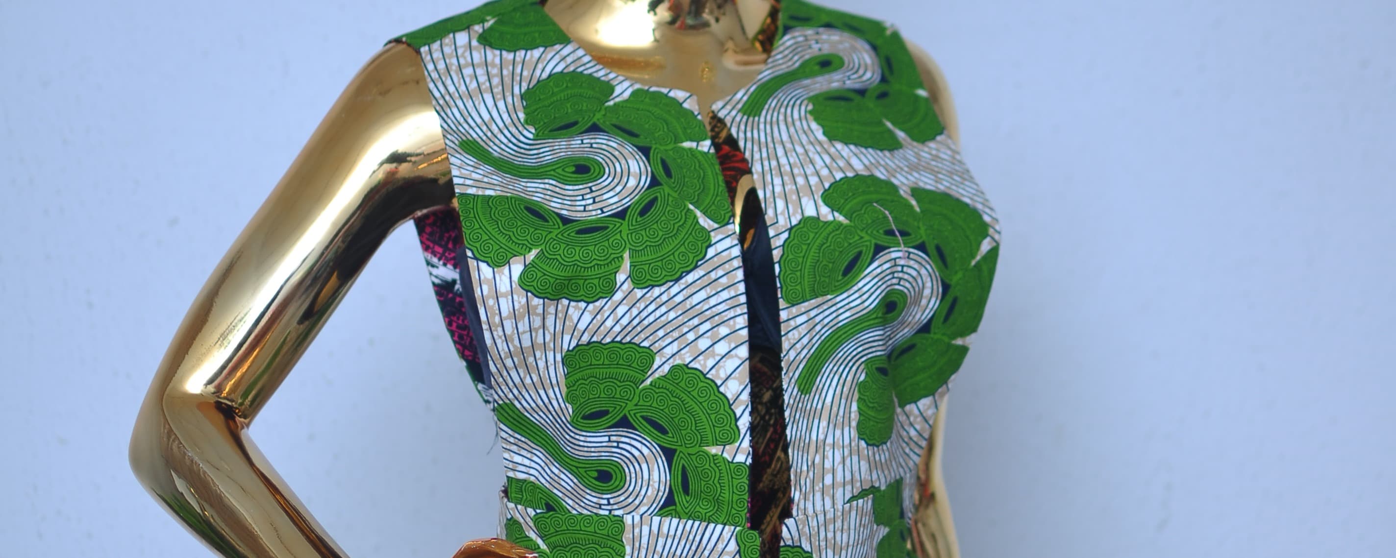 Fitted green and white Ankara print peplum top on a mannequin, the kind of reference picture you might save for its waist and silhouette.